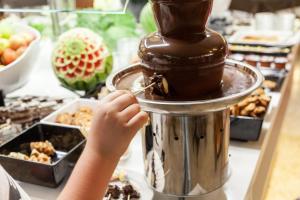 a child putting chocolate on top of a food processor at Hotel Xaine Park in Lloret de Mar