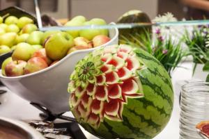 a melon with a flower on it next to a bowl of fruit at Hotel Xaine Park in Lloret de Mar