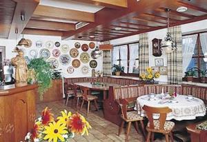 um restaurante com uma mesa e cadeiras num quarto em Pension Philippsreut "Zum Pfenniggeiger" em Philippsreut