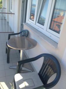 a table and chairs on a balcony with a table and window at SilvioDino SOBE in Crikvenica
