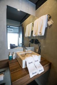 Un baño con lavabo, espejo y toallas. en The Rodman Hotel, en Chiang Mai