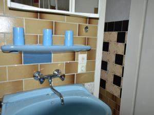 a bathroom with a sink with blue cups on the wall at Bungalow in Kühlungsborn-West in Kühlungsborn +33 photos