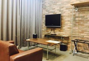 sala de estar con mesa y TV en una pared de ladrillo en Bear Hotel, en Sanxia