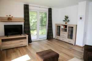 a living room with a flat screen tv and wooden floors at KapLuv Plau am See in Plau am See
