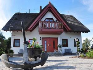 ein kleines Haus mit einem Boot davor in der Unterkunft Ferienwohnungen Zum Anker _ Objekt in Diedrichshagen