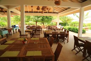 un ristorante con tavoli e sedie in legno e un patio di Les Manguiers de Guereo a Guéréo