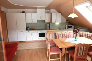 a kitchen with a table and chairs and white cabinets at Ferienwohnungen Graggaber in Mariapfarr