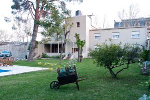 a cart sitting in the grass in front of a house at Hotel Papiros in Paysandú