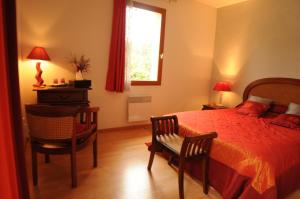 um quarto com uma cama, uma cadeira e uma janela em Les Pigeonnes em Groléjac