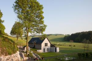 Une petite église blanche sur une colline avec un arbre dans l'établissement La Micheline-Design House Maredsous, à Bioul