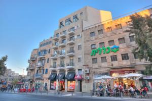 un edificio con gente sentada fuera de él en una calle en City Center Jerusalem, en Jerusalén