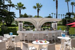 a restaurant with white tables and chairs and a bar at Hôtel Barrière Le Majestic Cannes in Cannes