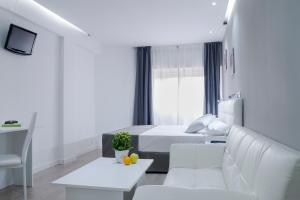 Habitación blanca con cama y sofá en Boutique Urban Madrid Serrano en Madrid
