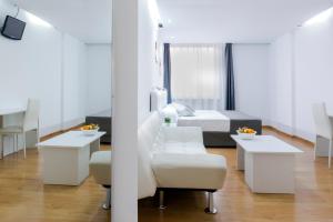 a white room with a bed and a chair and tables at Boutique Urban Madrid Serrano in Madrid