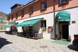 ein Gebäude mit Tischen und Sonnenschirmen auf einer Straße in der Unterkunft Hotel Prajer in Vodňany