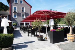 un patio con mesas, sillas y una sombrilla roja en Winzerhaus Gärtner - An der Loreley en Sankt Goar