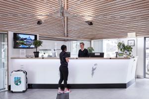 a woman standing at a counter in front of a woman at Araslöv Golf & Resort in Kristianstad