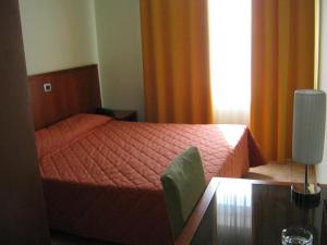 a bedroom with a bed with an orange bedspread and a table at Hotel San Martino in Cassibile