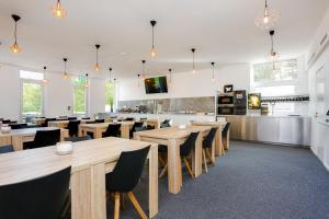 a restaurant with wooden tables and chairs and a kitchen at Almnäs Park Hotel in Södertälje