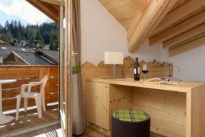 a room with a desk and a balcony with a view at Hotel Garni Lastei in Pozza di Fassa