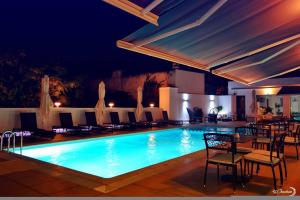 ein Pool mit Stühlen und Tischen in der Nacht in der Unterkunft Fredj Hotel in Tangier