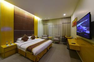 a hotel room with a bed and a flat screen tv at Hotel H - Sandhill Hotels Private Limited in Anand
