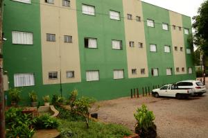 a green building with a white car parked in front of it at Hotel Capital in Cuiabá