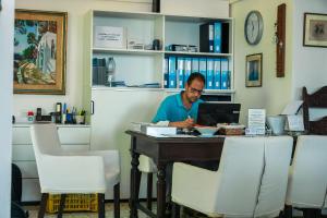 a man sitting at a table with a laptop at La Reginella Capri in Capri
