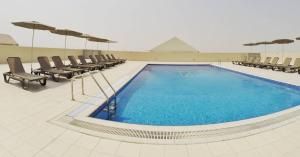 een groot zwembad met ligstoelen bij Le Park Hotel in Doha