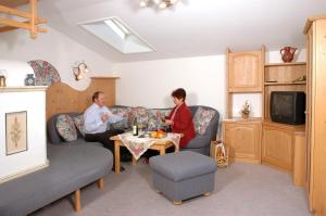 Ein Mann und eine Frau sitzen an einem Tisch im Wohnzimmer in der Unterkunft Haus Unterberg in Kössen