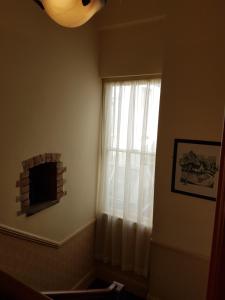 a window with a white curtain and a fireplace at Myles Creek in Kilkee