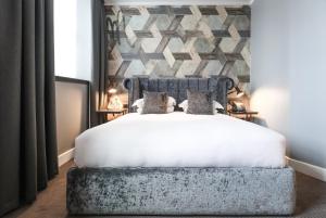 a bedroom with a white bed with a stone wall at Malmaison Hotel Leeds in Leeds