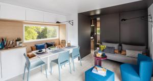a kitchen and living room with a table and blue chairs at Kanopée Village in Trévoux