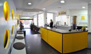 un restaurante con un mostrador amarillo con dos personas en él en Antonius Imperial Hotel, en Santo Antônio de Jesus
