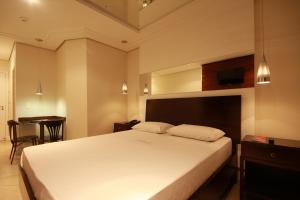 ein Schlafzimmer mit einem großen weißen Bett und einem Tisch in der Unterkunft Motel Atos ADULTS ONLY in São Paulo