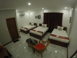 Habitación de hotel con 2 camas y mesa en Happy​​ Family Guesthouse, en Kampot