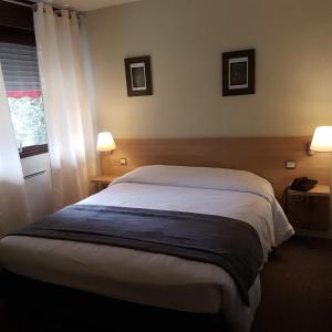 a bedroom with a bed and two lamps and a window at Hotel Restaurant Saint-Benoit in Gueugnon