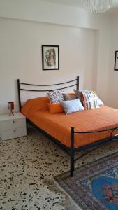 a bedroom with a bed with orange sheets and pillows at relax home in Marsala