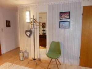 Zimmer mit einem grünen Stuhl und einem Spiegel in der Unterkunft Ferienwohnung Groß in Grafenau