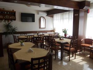 a restaurant with tables and chairs and a flat screen tv at Pension Larisa in Arad