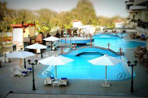ein großer Pool mit Sonnenschirmen, Tischen und Stühlen in der Unterkunft AIFU Hotel El Montazah Alexandria in Alexandria