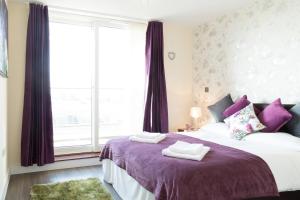 a bedroom with a bed with purple sheets and a window at Exquisite & Homely Penthouse, 2 mins walk from Cambridge Station, Big balcony, lift access, secured gated on-site parking, self check-in & SUPER Fast WIFI in Cambridge