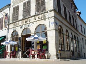 a building with tables and umbrellas in front of it at Les Epis d'Or in LʼIsle-sur-Serein