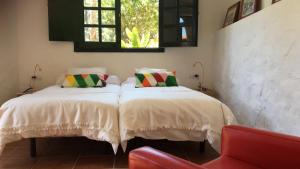テルデにあるFinca Hoya del Pozoのベッドルーム1室(ベッド2台、赤い椅子付)