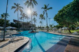 嘎林海斯港的住宿－Marulhos Suítes Resort by MAI，一座棕榈树和椅子的大型游泳池