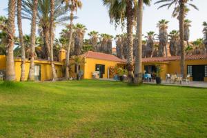 une maison jaune avec des palmiers et une cour dans l'établissement Finca Hoya del Pozo, à Telde