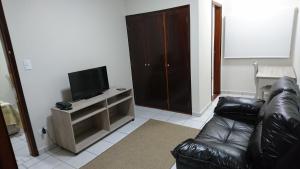 ein Wohnzimmer mit einem Ledersofa und einem Flachbild-TV in der Unterkunft Hotel Premium Flat Ourinhos in Ourinhos