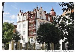 un gran edificio blanco con una valla delante en Apartmán Vila Bayer, en Karlovy Vary