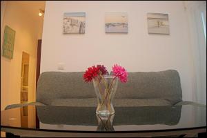eine Vase mit Blumen auf einem Tisch vor einer Couch in der Unterkunft Apartamento Andujar in Cádiz