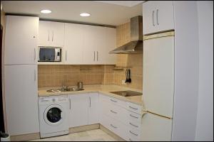 eine Küche mit weißen Schränken und einer Waschmaschine in der Unterkunft Apartamento Andujar in Cádiz